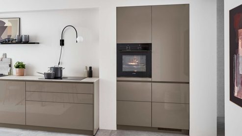 Einbauküche Nobilia® aus Holz in Grau nobilia® Einbauküche Novalux mit Hochglanzfronten und BORA Muldenlüfter Taupegrau & Eiche Como - zweiteilig