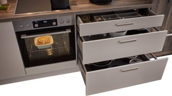 Einbauküche WERT KÜCHE® aus Holz in Beige WERT KÜCHE® Nora mit AEG Einbaugeräten Muschelweiß & Virginia Eiche – zweizeilig